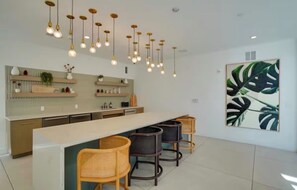 Uma cozinha moderna com bancada comprida, luminárias pendentes e banquetas.
