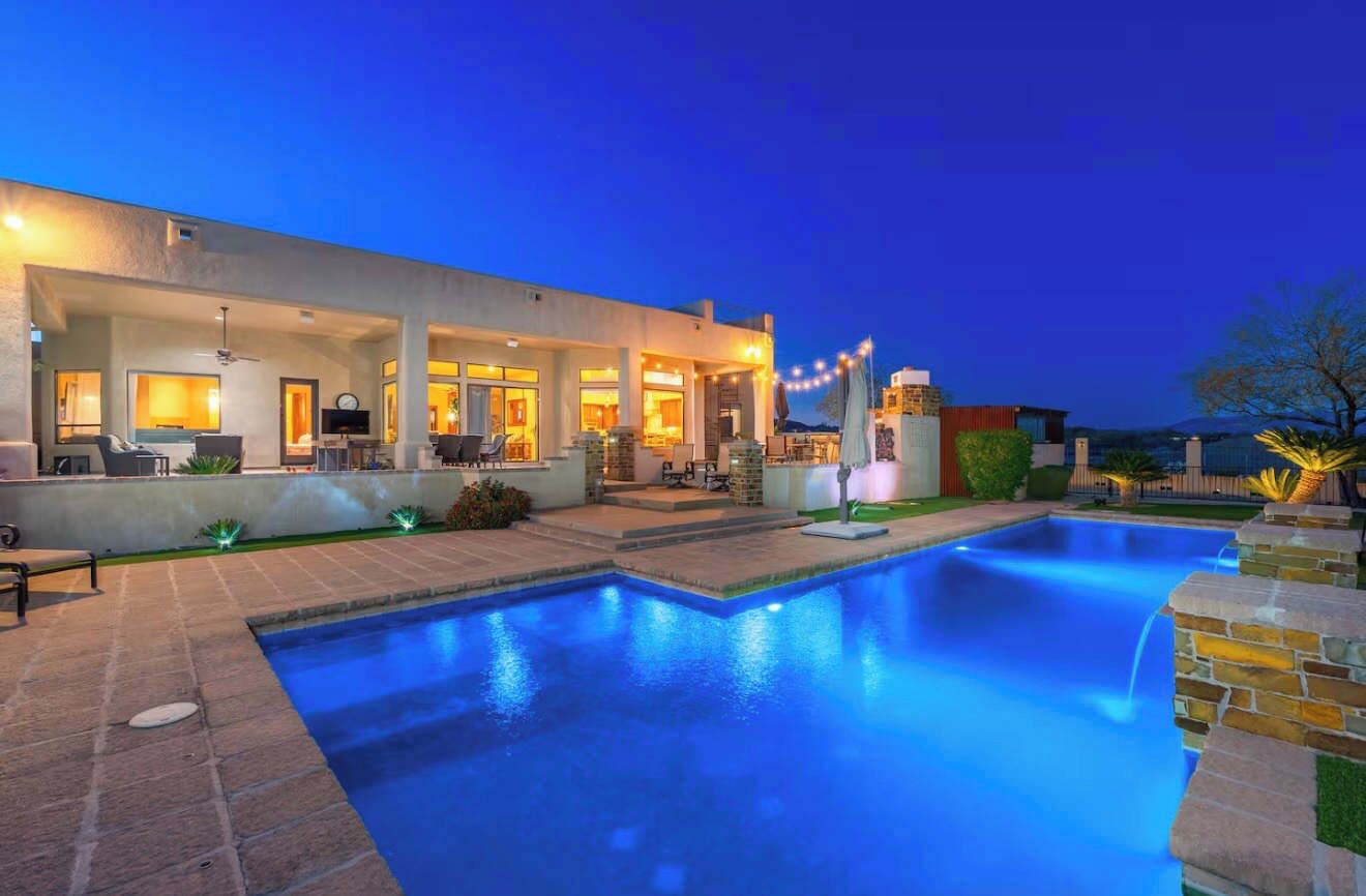 Une maison moderne dotée d’une piscine, d’un espace salon extérieur et d’une terrasse bien éclairée.