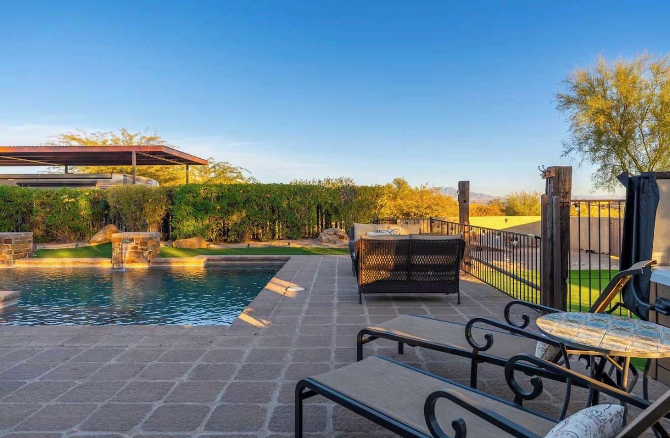 A poolside area with a covered seating area, a barbecue grill, and a fenced garden.