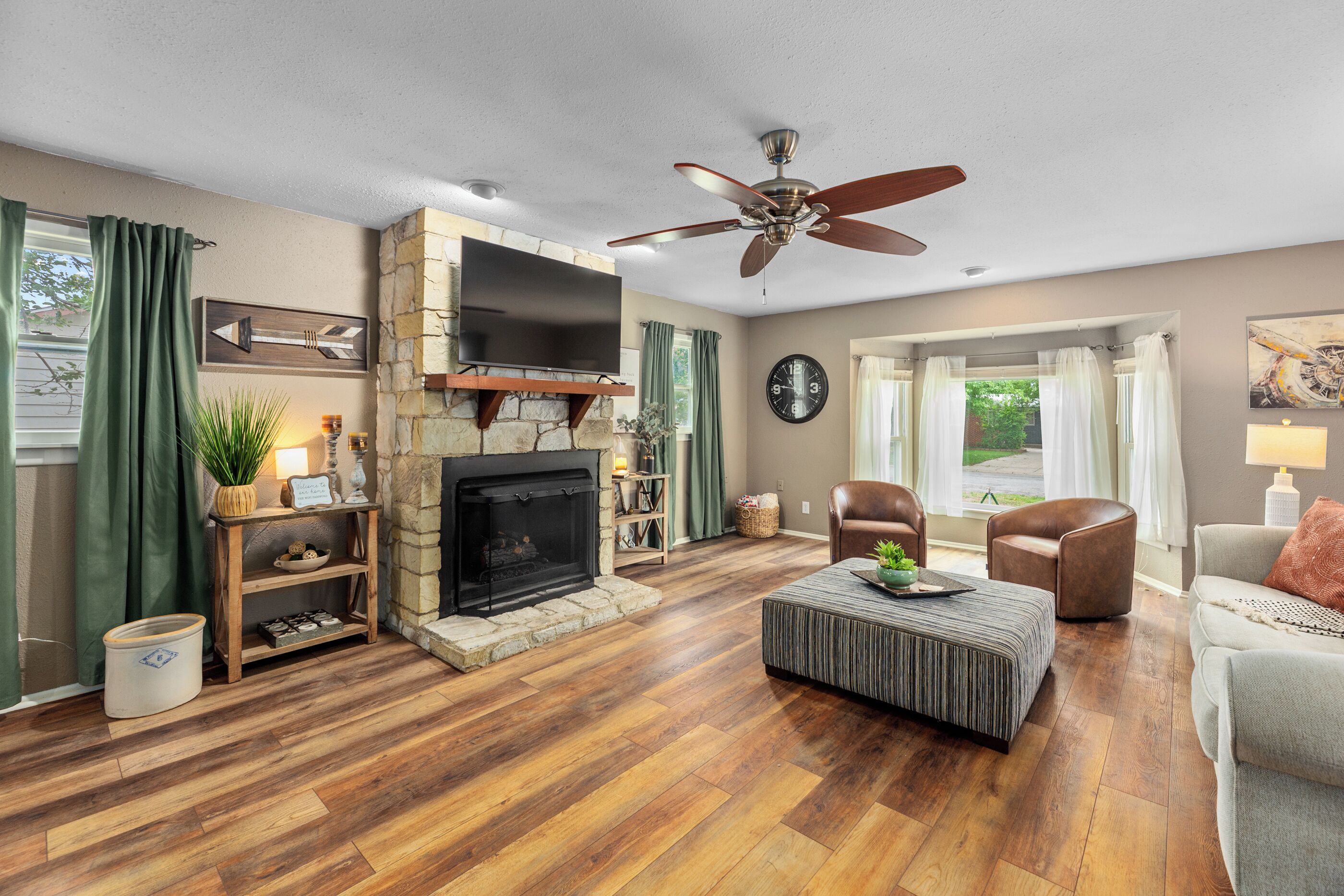 A living room with a fireplace, a ceiling fan, a television, and a sofa.