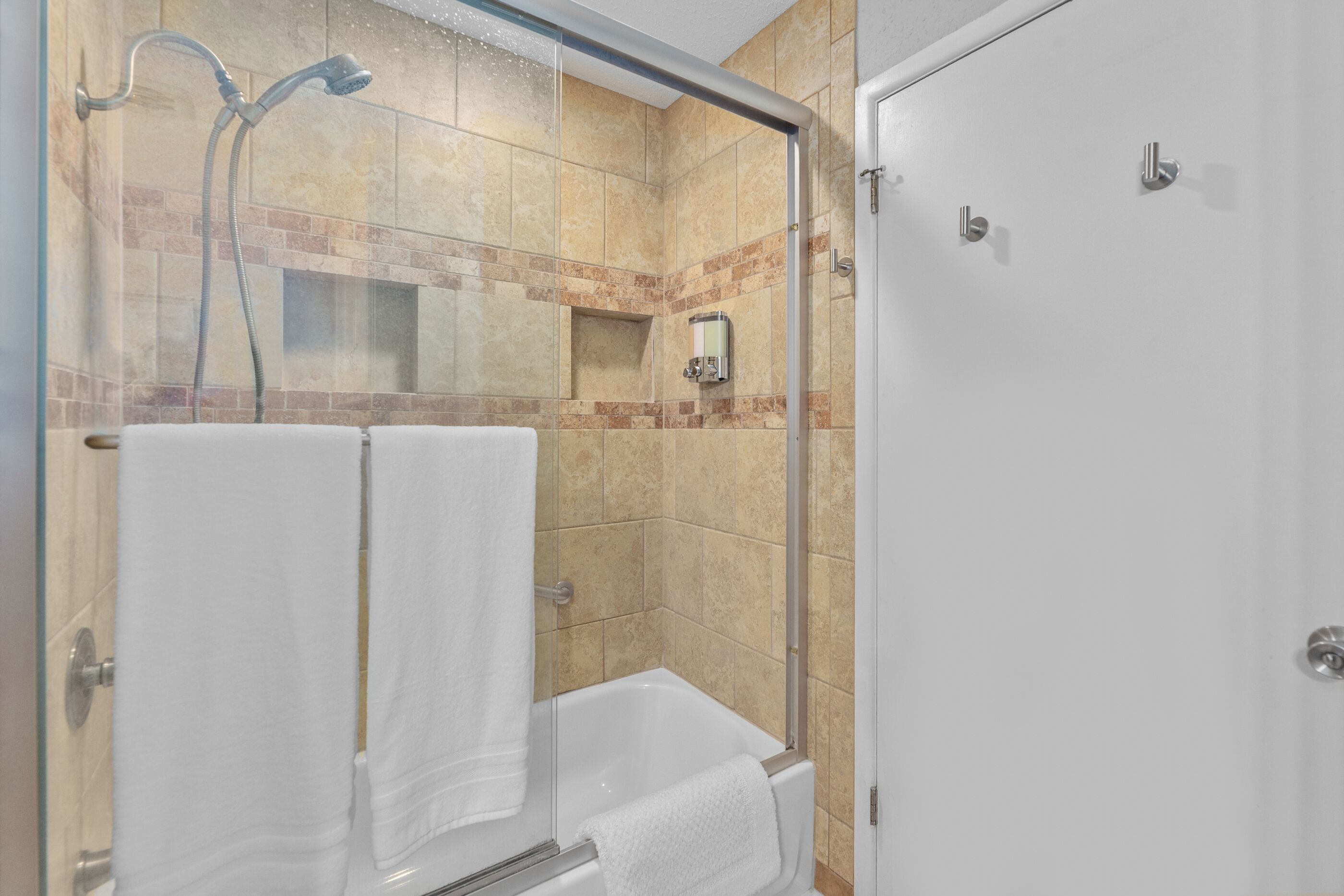 Une salle de bain avec une douche à parois de verre, une baignoire blanche et un porte-serviettes.