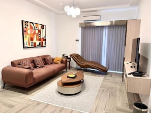 Una sala de estar moderna con un sofá, una mesa de centro, un sillón reclinable, un escritorio y un televisor.
