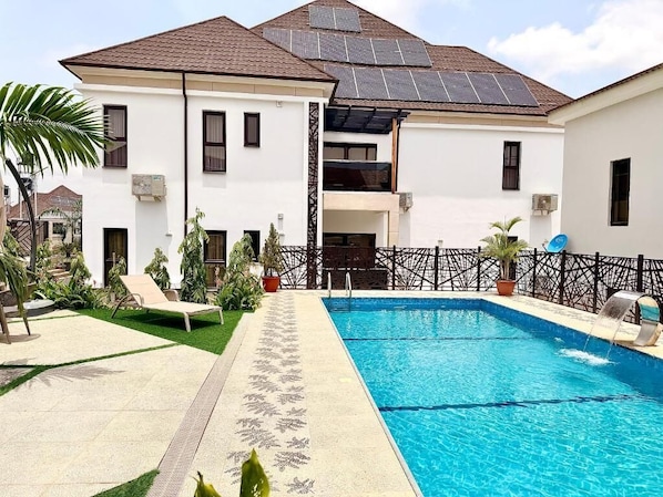 Un edificio residencial con piscina, paneles solares en el techo y un patio amurallado.