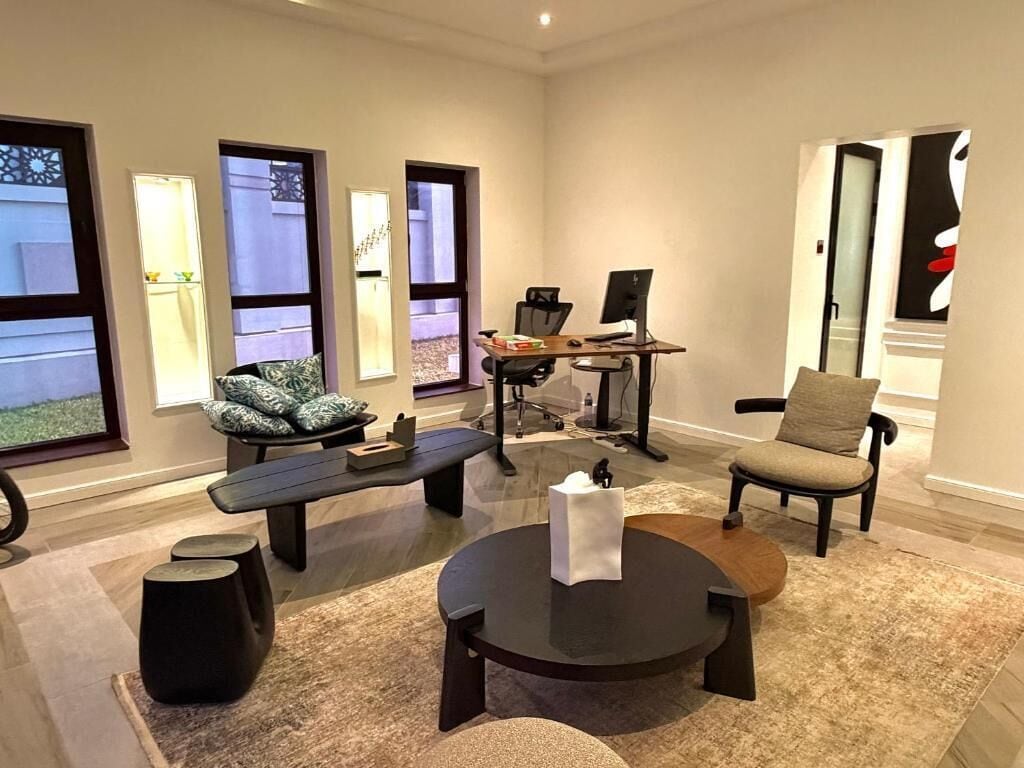 A modern living room with a desk, two chairs, a round coffee table, and a sofa.