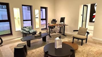 A modern living room with a desk, two chairs, a round coffee table, and a sofa.