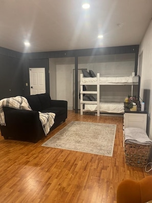 A room with a bunk bed, a black sofa, a small table, and a wicker basket. - Peaceful 1-bedroom apartment in charming Laramie perfect for getaway. (Laramie)