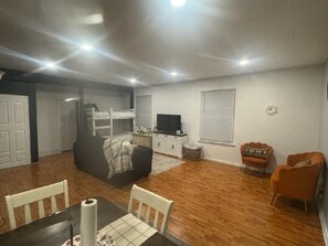 A living room with a sofa, a television, and a dining area with a table and chairs. - Peaceful 1-bedroom apartment in charming Laramie perfect for getaway. (Laramie)