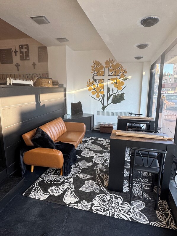 Un salon moderne avec un canapé en cuir, une table basse et une grande fenêtre donnant sur la rue.