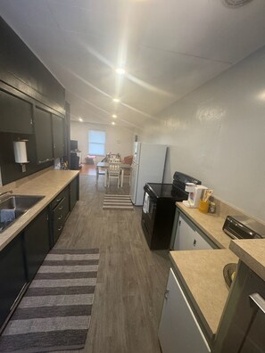 A compact kitchen with a sink, stove, refrigerator, and a dining area with chairs and a table. - Peaceful 1-bedroom apartment in charming Laramie perfect for getaway. (Laramie)
