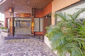 A hotel entrance with a tiled floor, a wooden ceiling, and a glass door with a decorative design. - Townhouse Rajkot Bus Stand (Rajkot)