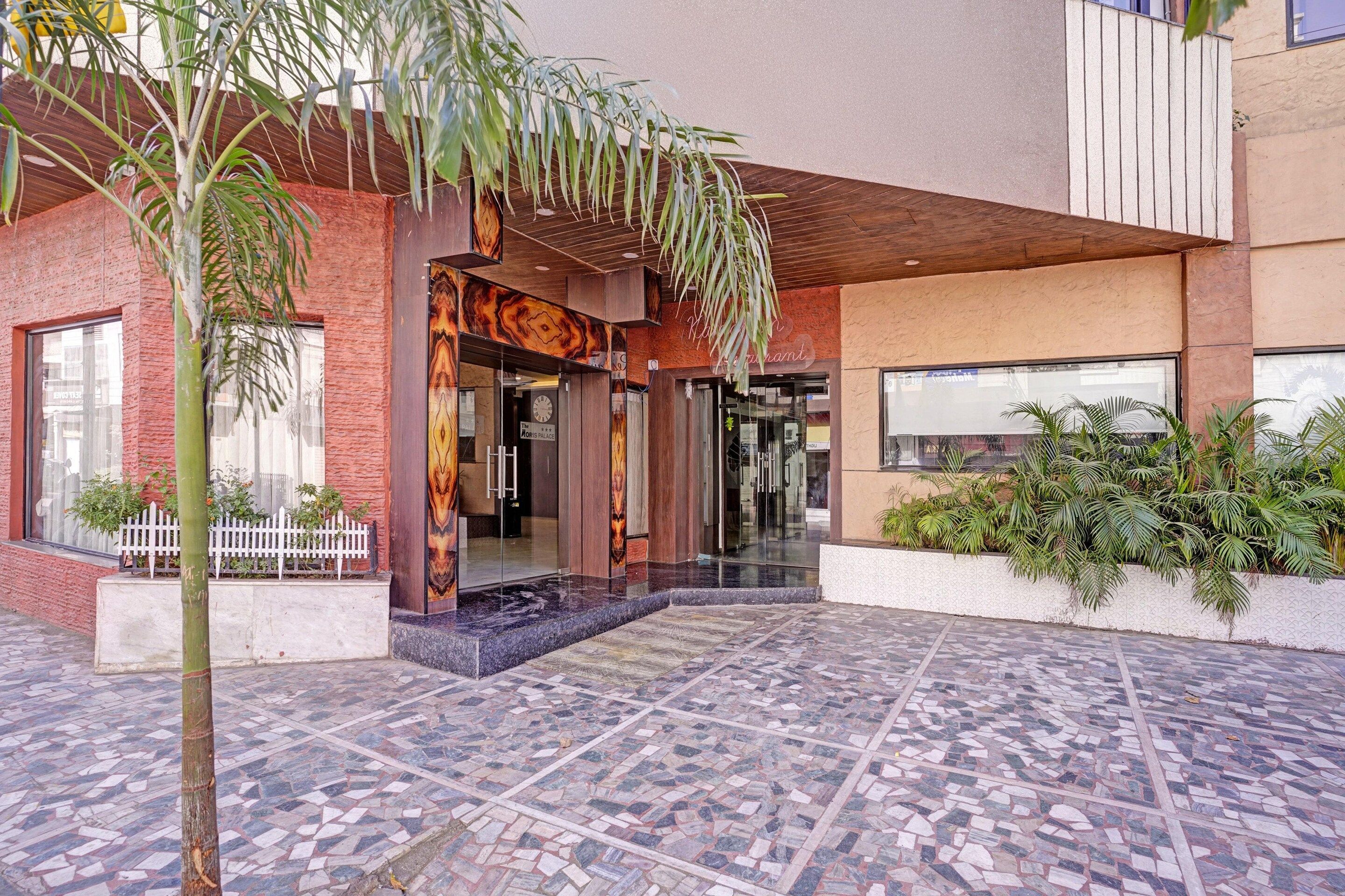 A hotel entrance with a tiled patio, a white picket fence, and a palm tree.
