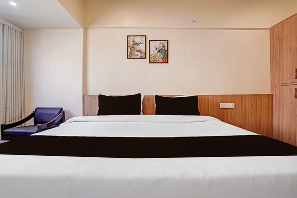 A hotel room with a bed, a chair, and two wall-mounted paintings.