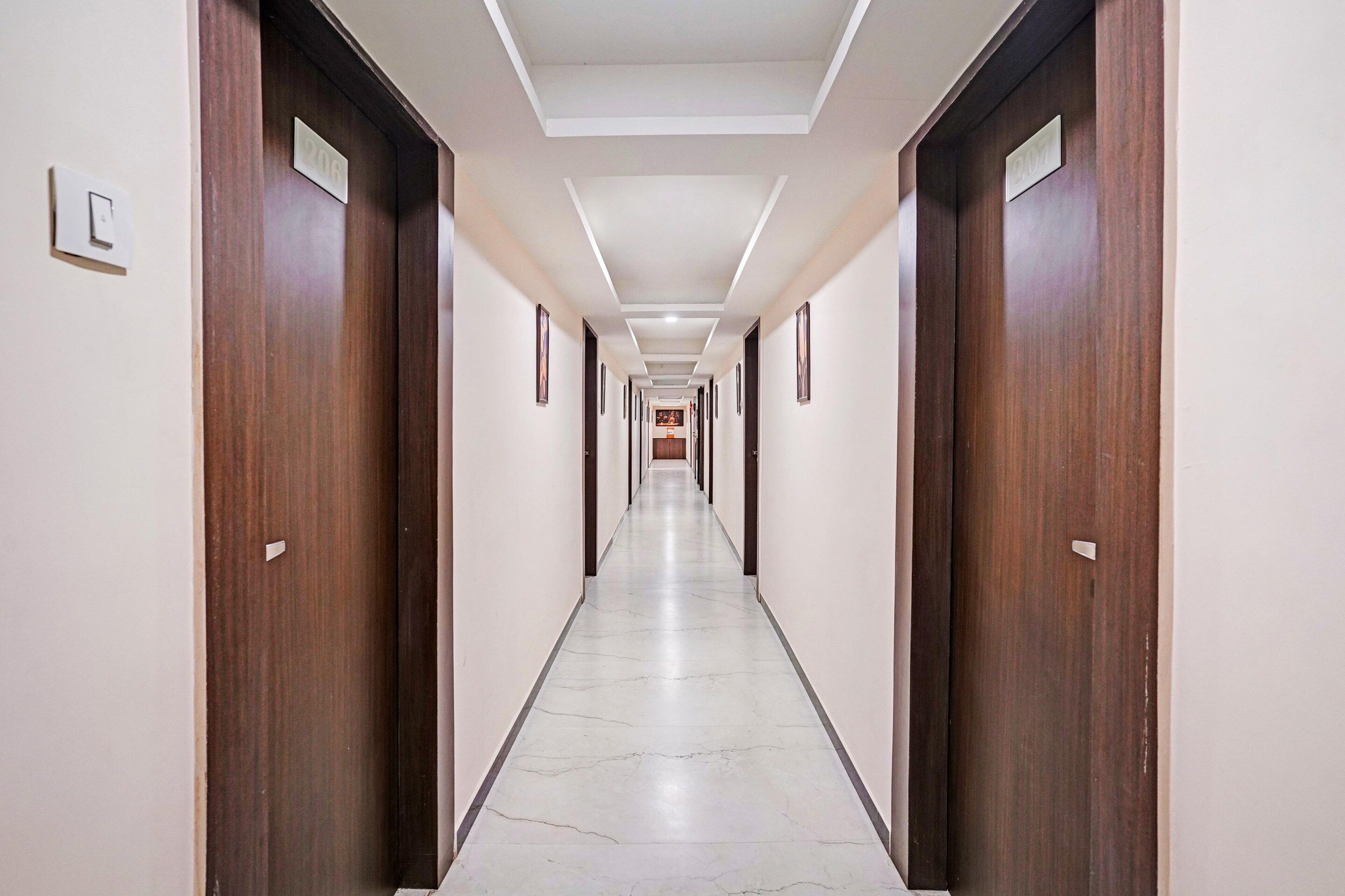 A long, narrow hotel corridor with wooden doors on either side and a tiled floor.
