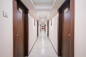A long, narrow hotel corridor with wooden doors on either side and a tiled floor.