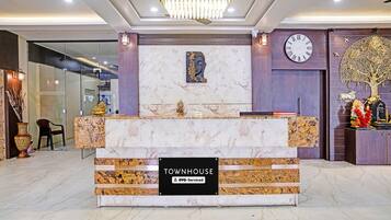 A reception desk with a marble top, a clock, and a Buddha statue above it.