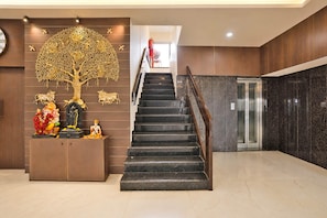 A staircase with a handrail leading to an elevator. - Townhouse Rajkot Bus Stand (Rajkot)