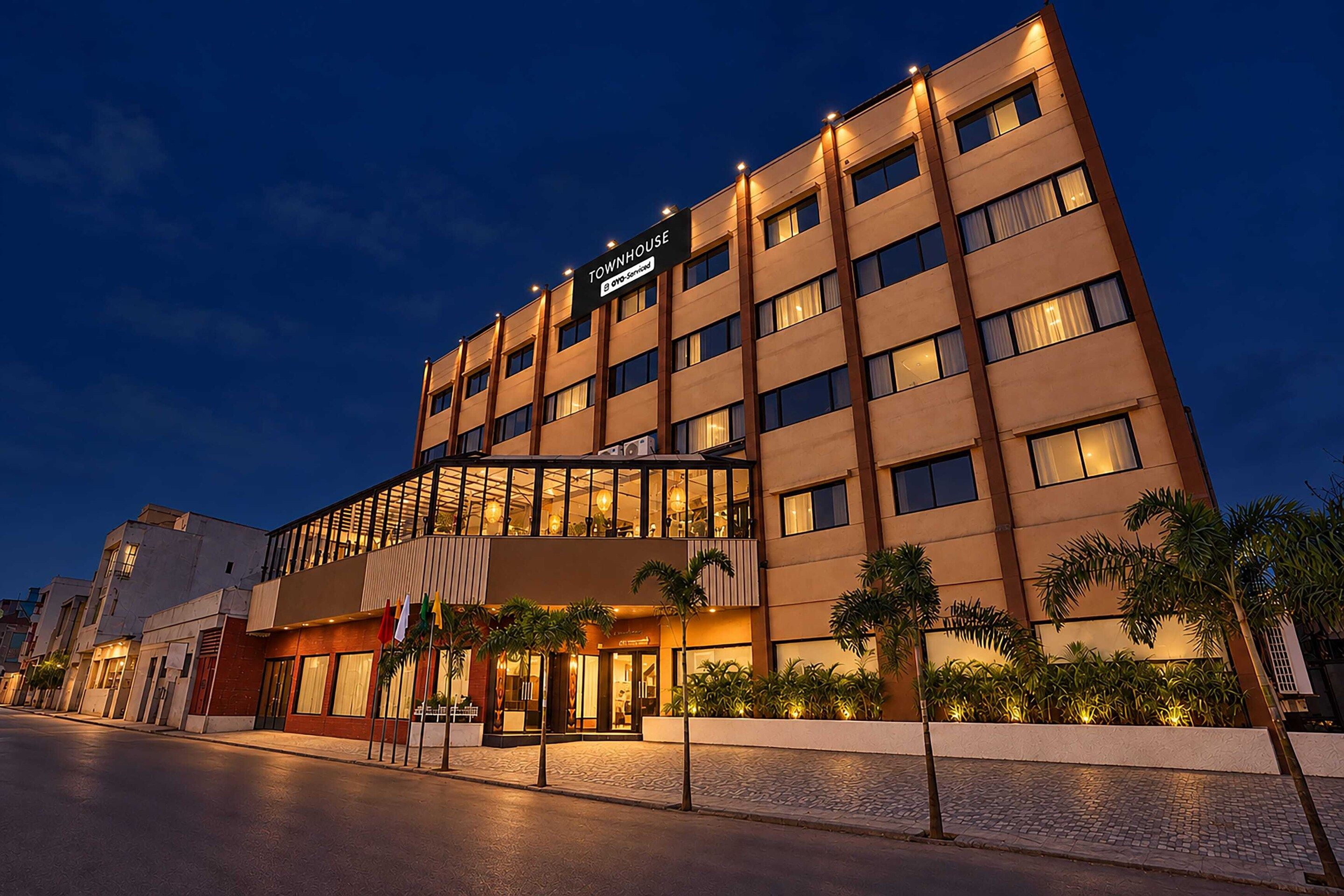 Een hotel met meerdere verdiepingen, modern vormgegeven, met een opvallende entree met glazen deuren en een bord dat het een appartementenhotel aanduidt.
