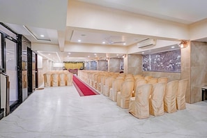 A hotel conference room with rows of chairs, a red carpet, and a stage at the front. - Townhouse Rajkot Bus Stand (Rajkot)