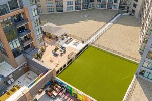 A multi-story building with a rooftop terrace, outdoor seating area, and a fenced sports field. - Flats DT + Balcony + Dog Park + On-site Parking (Cleveland)