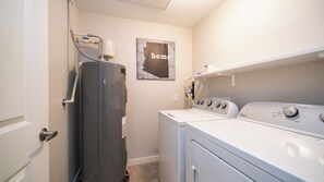 A laundry room with a water heater, a washing machine, and a dryer.