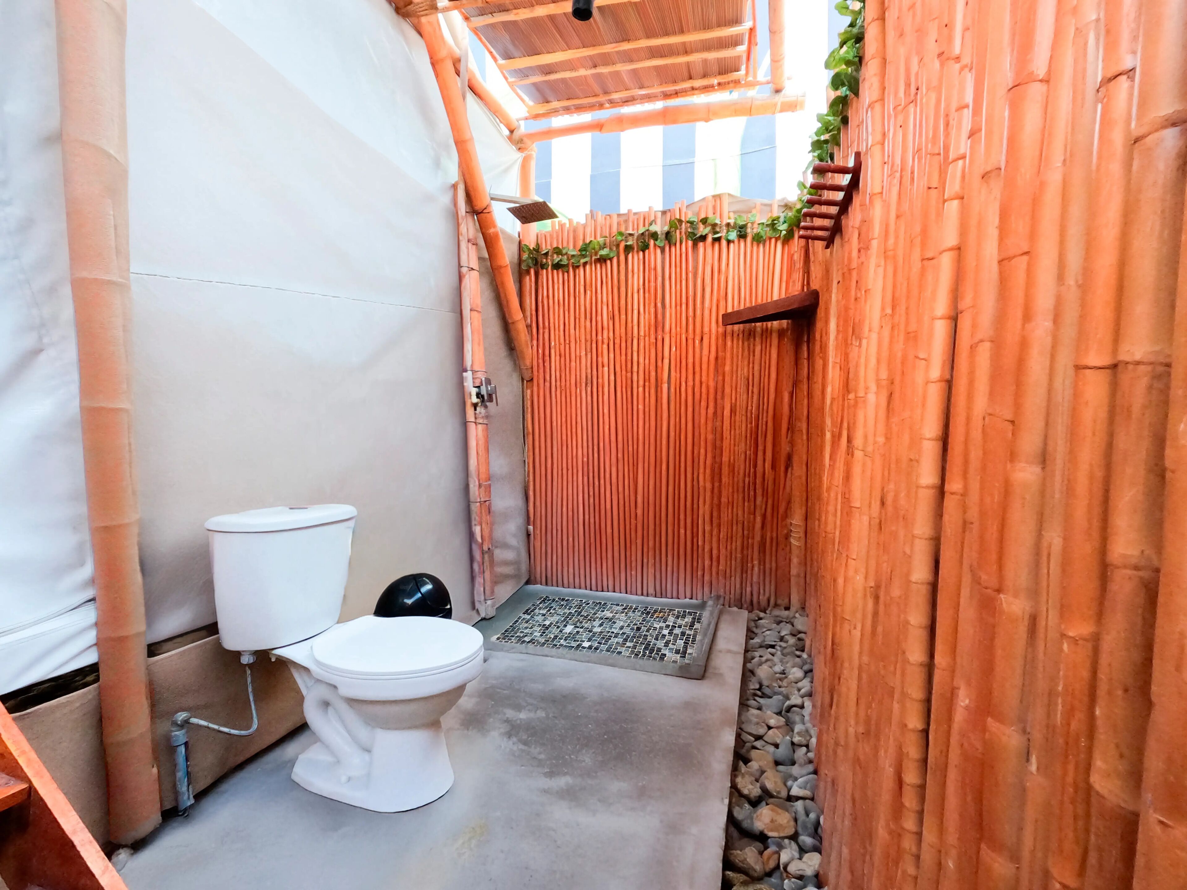 Een compacte, afgesloten badkamer met toilet, douche en een wand van bamboe.