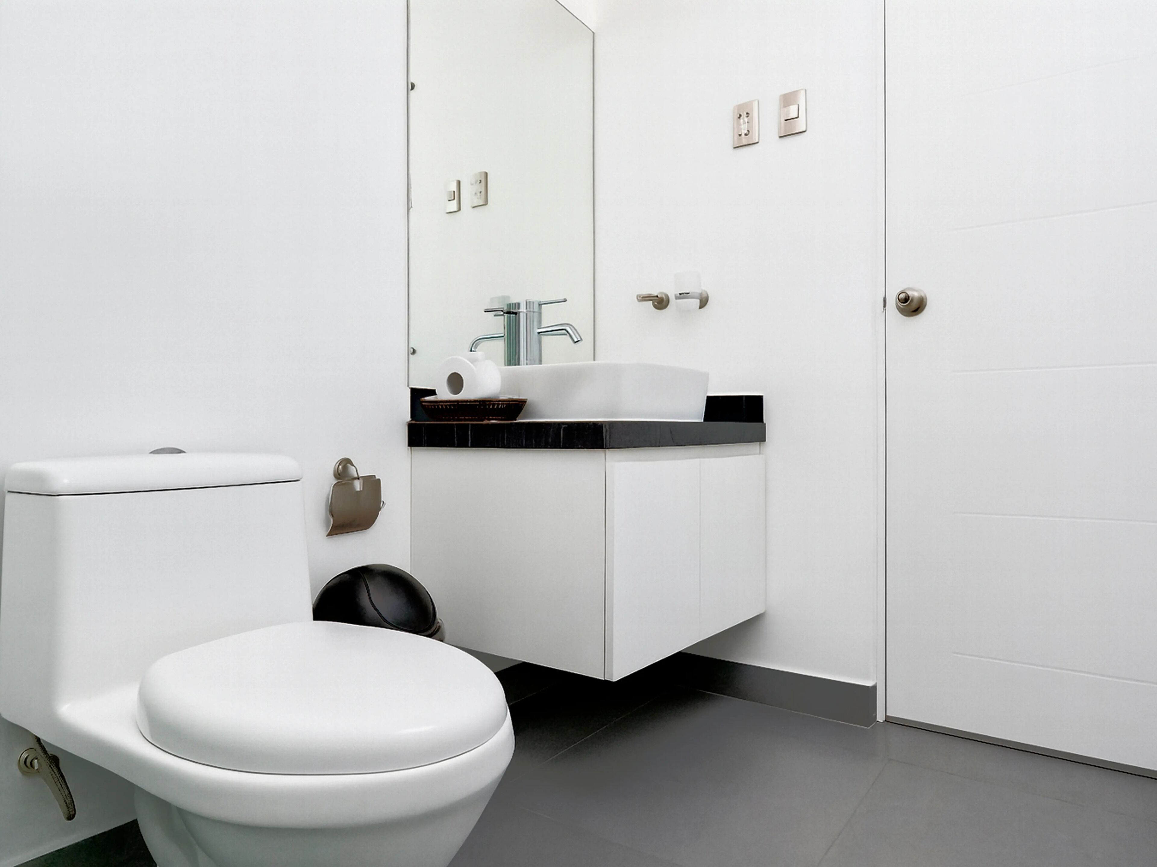 A modern bathroom with a toilet, a sink, and a mirror.