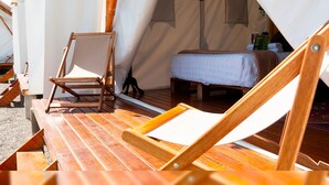 Alojamiento con tienda de campaña, una cama, una silla de madera y una mesa.