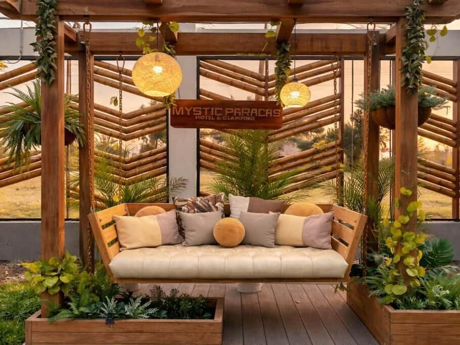Une pergola en bois sur laquelle est accrochée une enseigne indiquant : « MYSTIC PARICAS HOTEL & CLIMBING ».