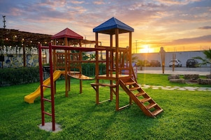 Un parque infantil con tobogán y estructuras para escalar, con el atardecer de fondo.