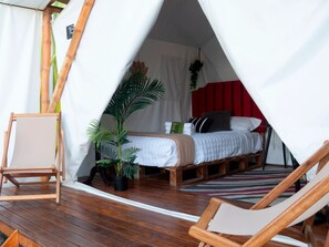 Una habitación con carpa, una cama, una silla y una planta en maceta.