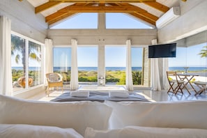Ein Schlafzimmer mit einem großen Bett, einem Fernseher und Meerblick.