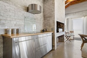 A modern kitchen with stainless steel appliances, a wooden countertop, and a brick wall. - The Kervs - Four Bedroom House, Sleeps 8 (Saint Helena Bay)