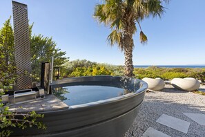 Ein Whirlpool mit Blick auf das Meer, umgeben von viel Grün und einer Palme.