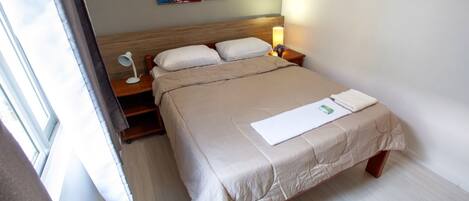 Ein Hotelzimmer mit Bett, Nachttischen, einer Lampe und Bildern an der Wand.