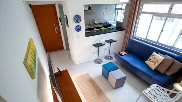 Un espacio habitable moderno con cocina, un sofá azul, una mesa de centro y un televisor.