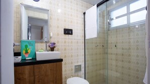Baño con ducha, inodoro y lavabo con espejo.