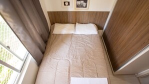 A bed with a headboard, two pillows, and a folded towel. There are two framed pictures on the wall above the bed. - StayHome Florianópolis - 6 Hóspedes  (Florianópolis)