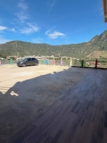 Un estacionamiento con un automóvil, una vista de la montaña y un edificio al fondo.