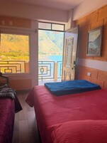 Una habitación de hotel con una cama, una silla, vista a un lago y una montaña.