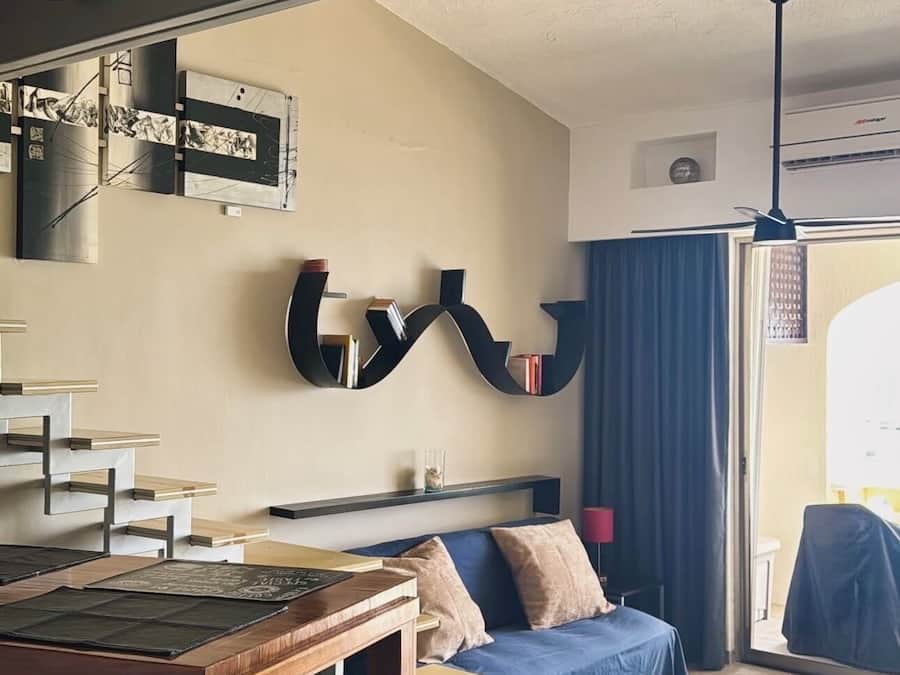 A modern living room with a sofa, a dining table, and a unique black bookshelf.