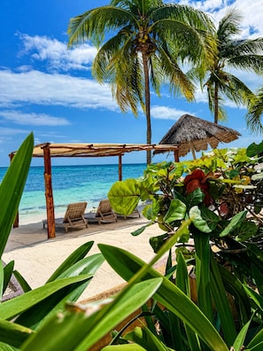 Een privéstrand, wit zand, ligstoelen aan het strand, parasols