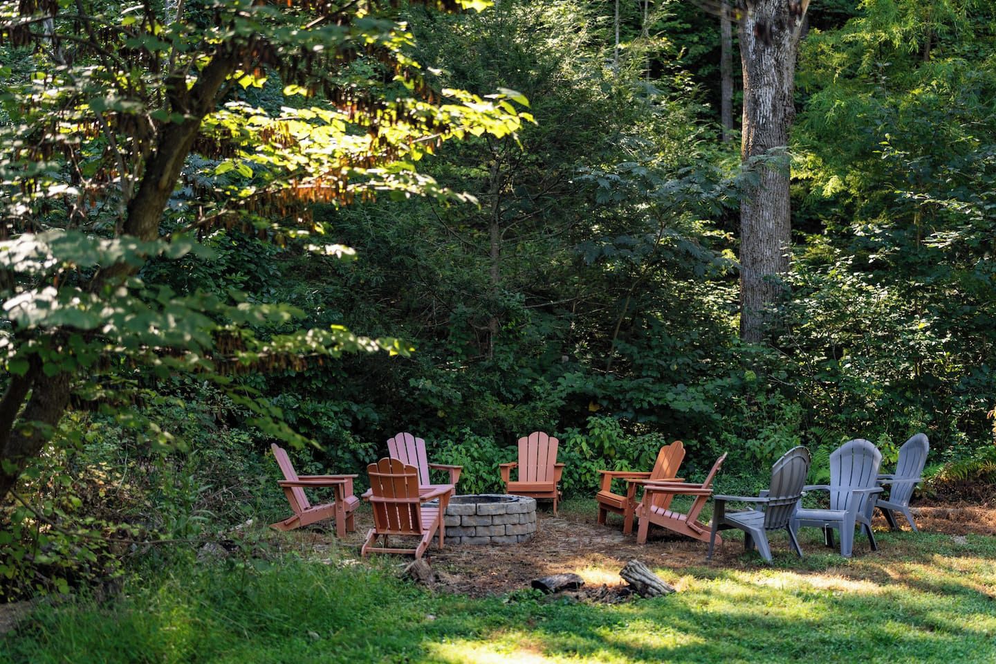 Zona boscosa amb espais exteriors, incloent cadires Adirondack i una xemeneia.