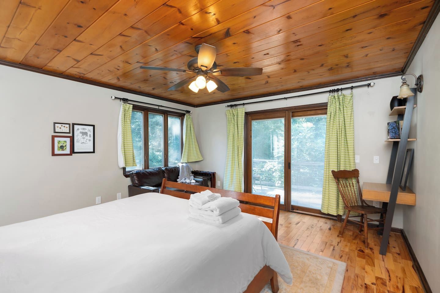 A bedroom with a bed, a desk, a chair, and a ceiling fan.