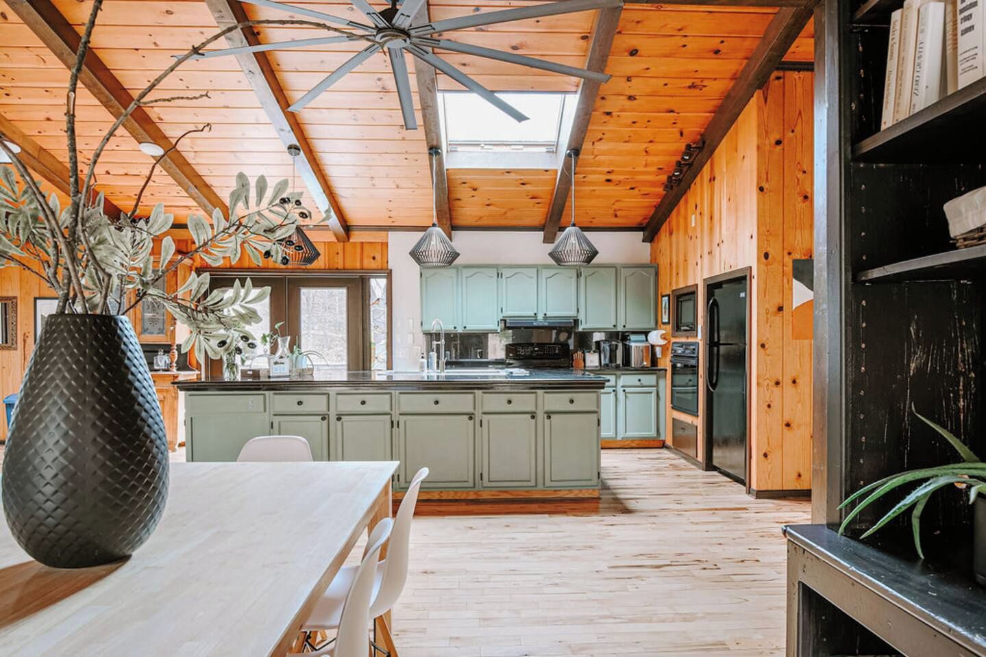 A spacious kitchen with wooden beams, a central island, and a dining area with a table and chairs.