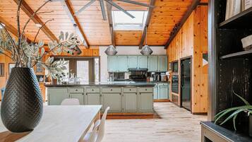 A spacious kitchen with wooden beams, a central island, and a dining area with a table and chairs.