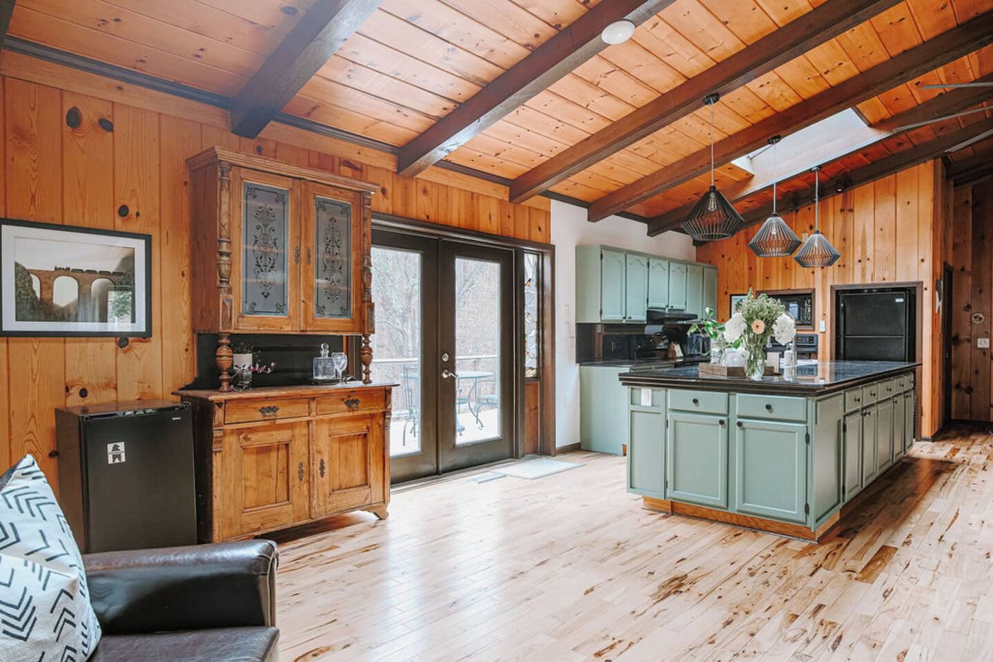 A spacious kitchen with wooden cabinets, a central island, and pendant lighting.