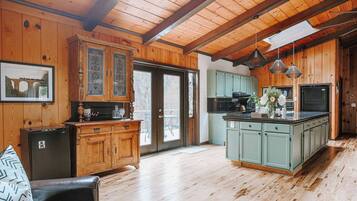 A spacious kitchen with wooden cabinets, a central island, and pendant lighting.
