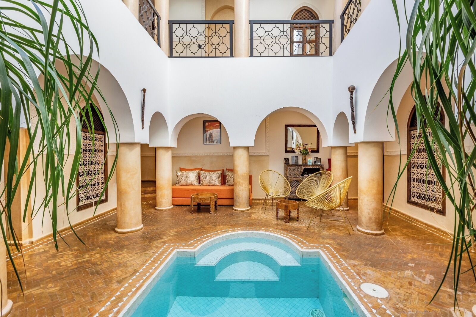 Une cour spacieuse dotée d’une piscine, d’un espace salon et d’arcs décoratifs.
