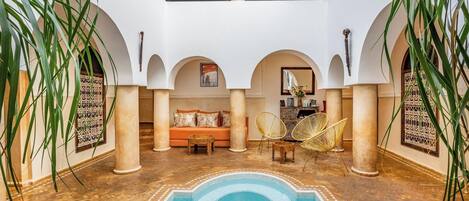 A spacious courtyard with a pool, seating area, and decorative arches.