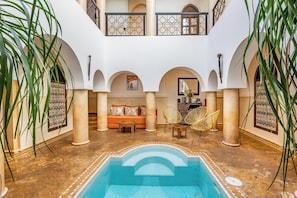 Un amplio patio con piscina, zona de estar y arcos decorativos.